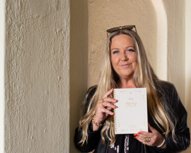 Porträttfotografering av Helena Magdalena Ivekrans Nätt med sin bok, använd i personligt varumärkesbyggande Porträtt av Helena Magdalena Ivekrans Nätt som håller sin bok, fotograferad i naturligt ljus