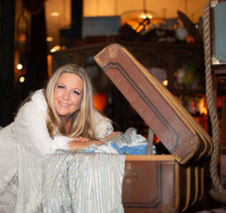 Porträttfotografering av Helena-Magdalena Ivekrans-Nätt på Liseberg Grand Curiosa Hotel, i samband med kreativt arbete och vistelse Porträtt av Helena-Magdalena Ivekrans-Nätt vid en resväska på Liseberg Grand Curiosa Hotel, fotograferad i varm miljöbelysning